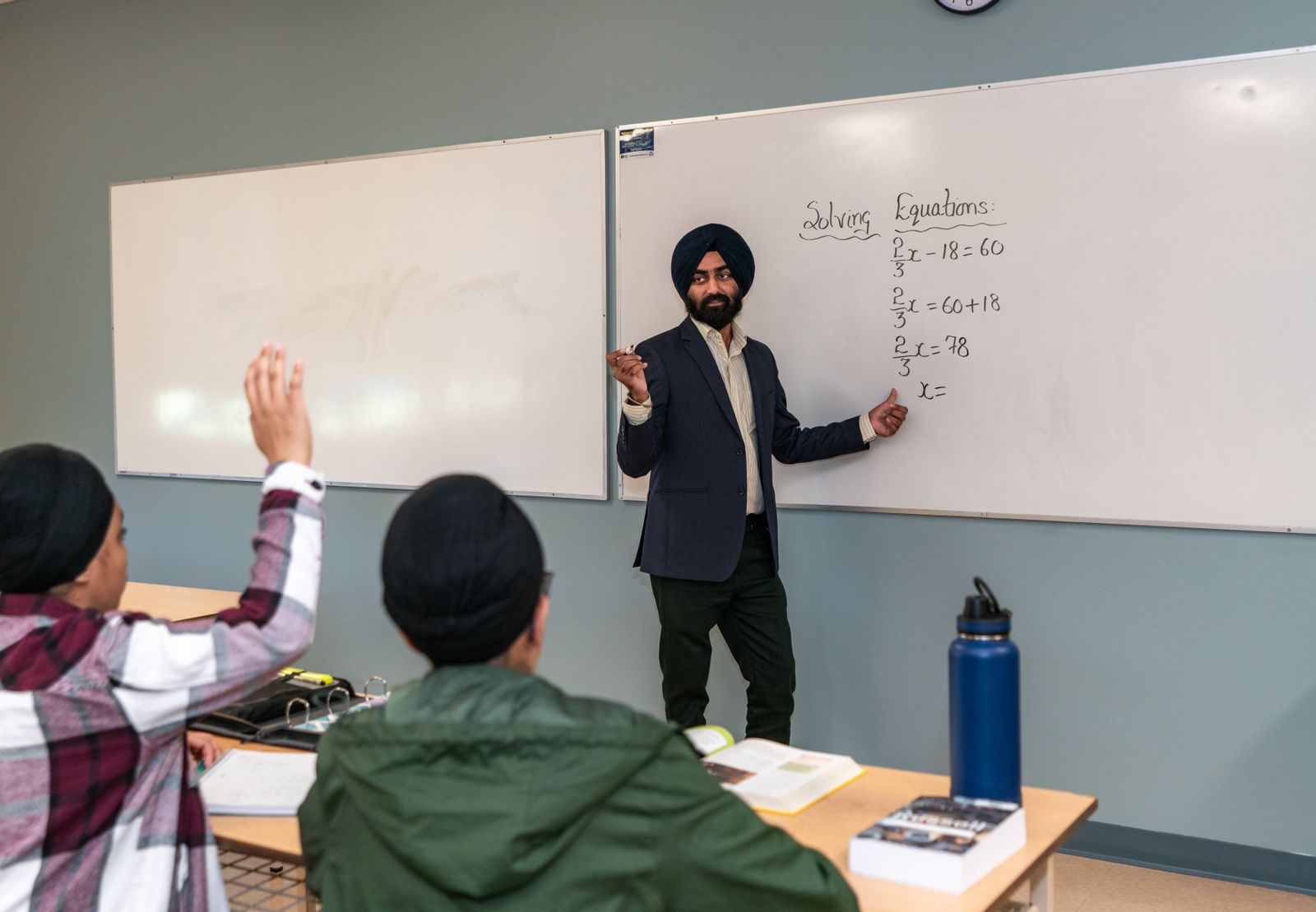 A student watching a recorded video lesson on a phone beside an open notebook